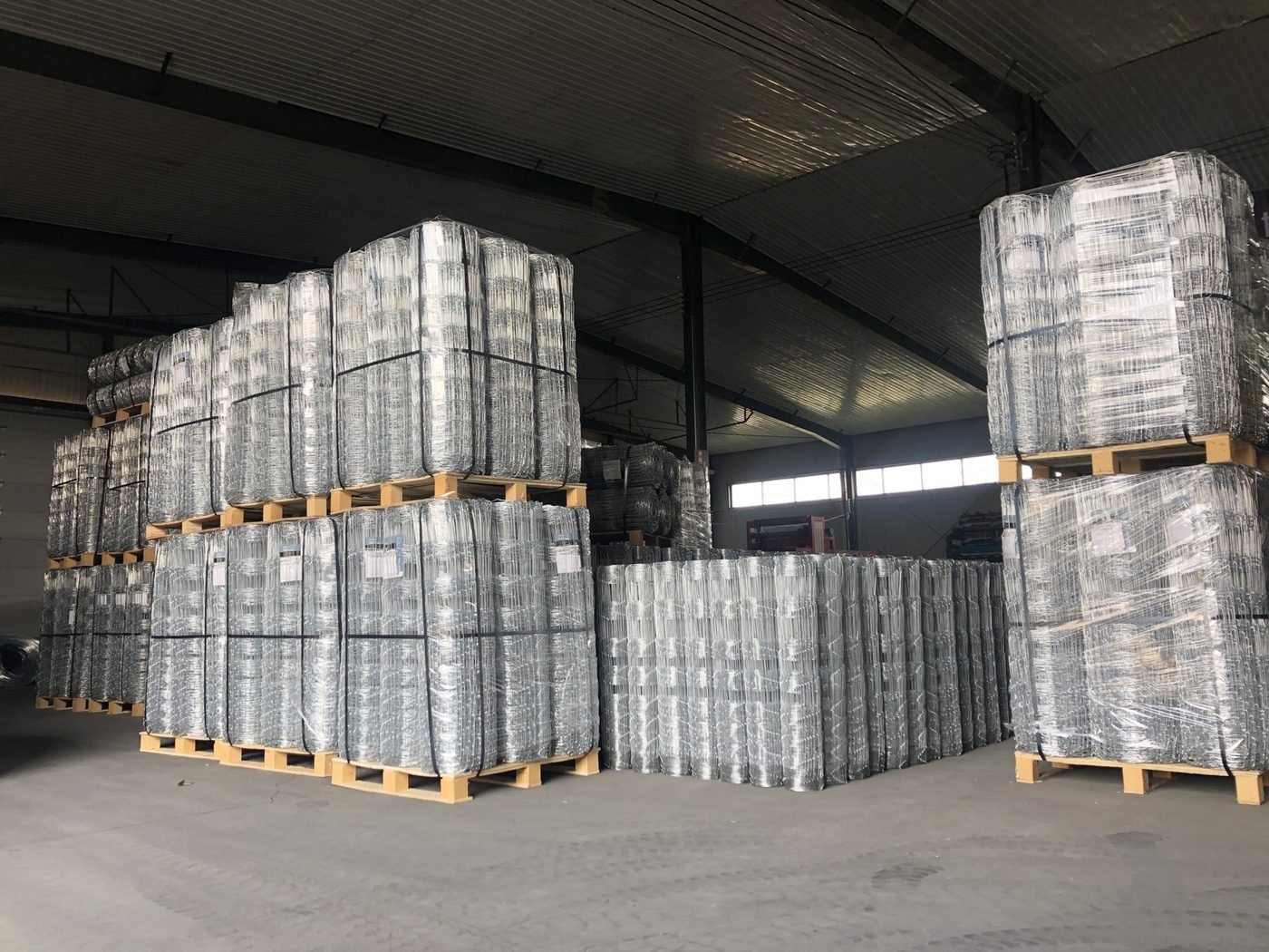 Galvanized cattle fence wire rolls stacked in our factory warehouse, ready for export