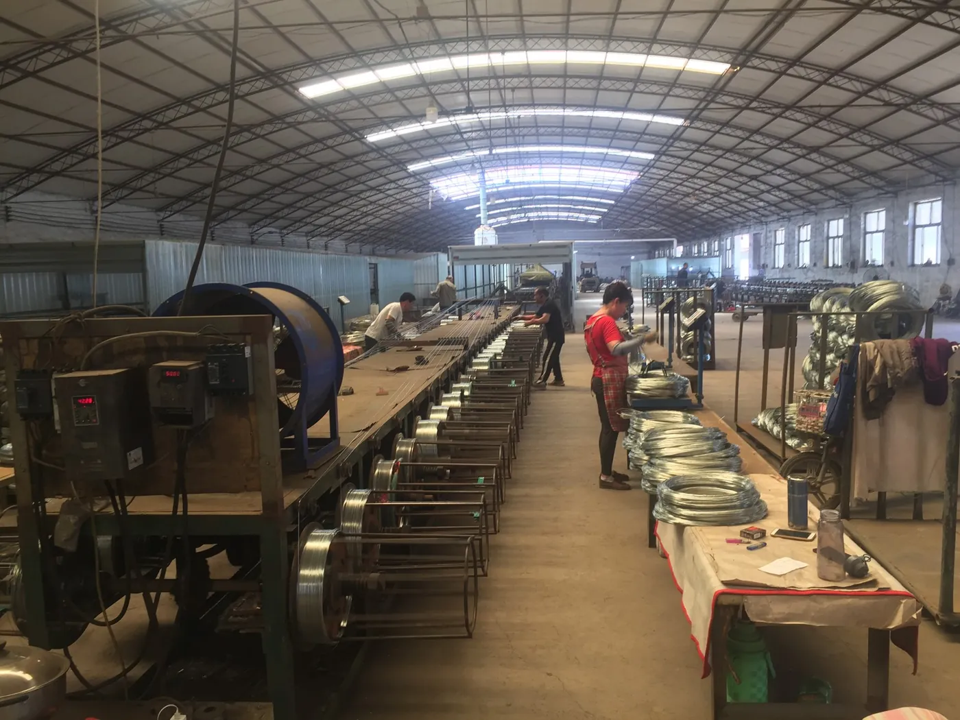 Manufacturing technicians inspecting fence wire production equipment